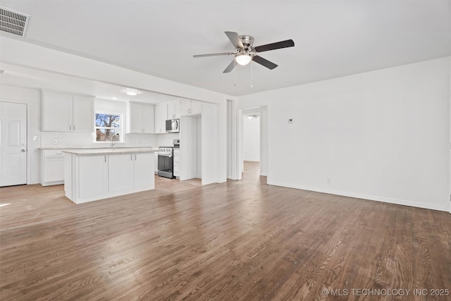 unfurnished living room featuring a sink, visible vents, light wood-style flooring, and ceiling fan