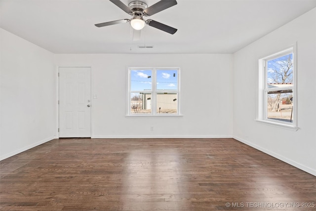 empty room featuring dark wood-style floors, visible vents, and a wealth of natural light