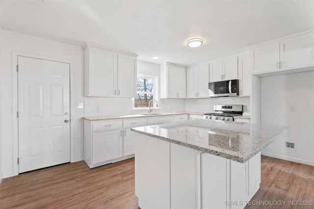 kitchen featuring a sink, light wood-type flooring, appliances with stainless steel finishes, and white cabinetry