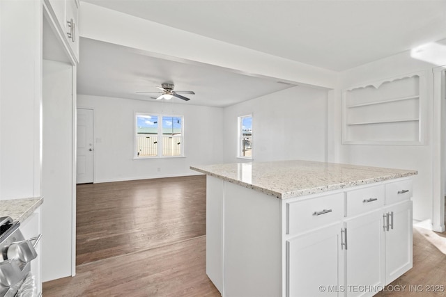 kitchen featuring open floor plan, light wood-style flooring, white cabinetry, a ceiling fan, and range