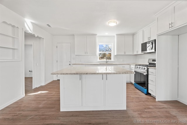 kitchen with white cabinetry, wood finished floors, a kitchen island, and stainless steel appliances