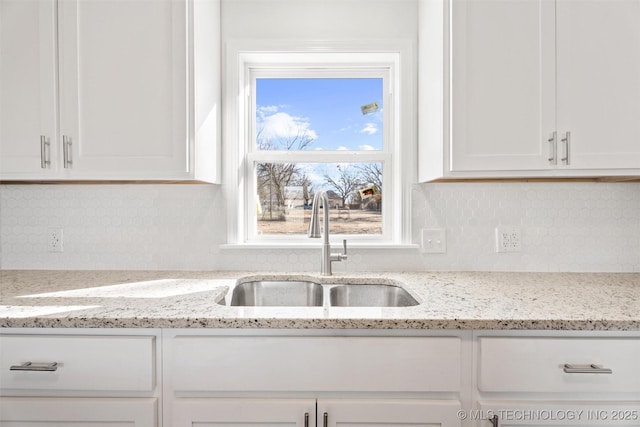 kitchen featuring a sink, tasteful backsplash, and white cabinetry