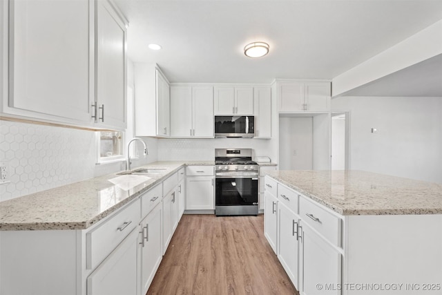 kitchen featuring a sink, light wood-style floors, white cabinetry, and stainless steel appliances