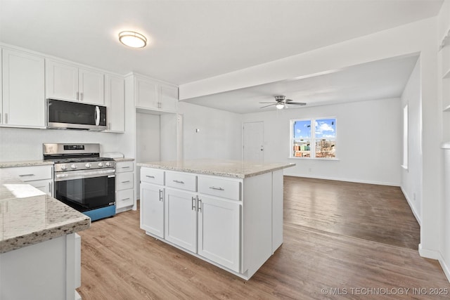 kitchen with stainless steel appliances, light stone countertops, white cabinets, and light wood finished floors