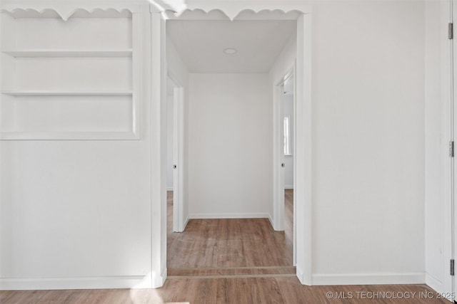 hall with baseboards and wood finished floors