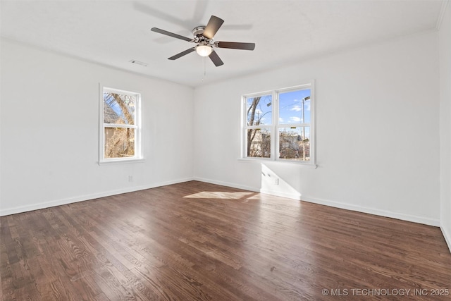 spare room featuring a wealth of natural light, baseboards, and wood finished floors