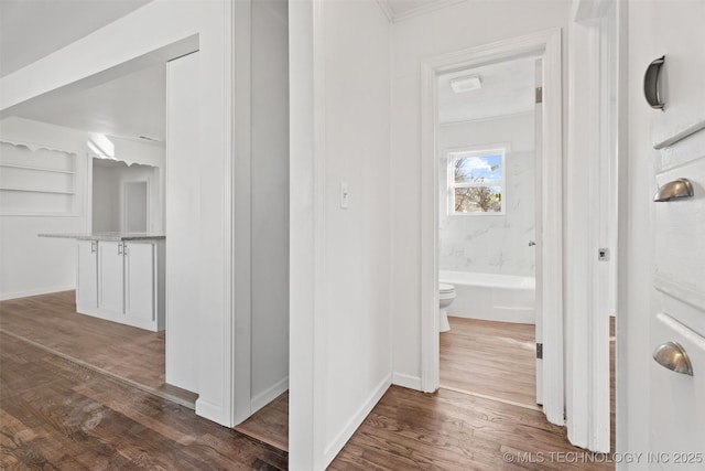 hallway featuring dark wood finished floors, baseboards, and ornamental molding