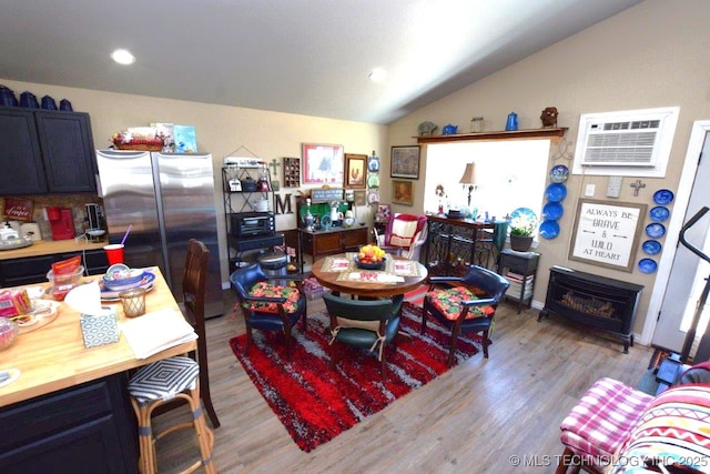 interior space with light wood-type flooring, a wall mounted AC, and lofted ceiling