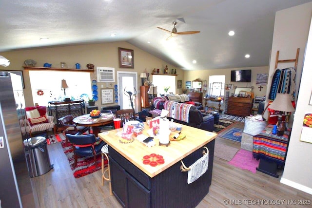 kitchen featuring a center island, open floor plan, light wood-type flooring, lofted ceiling, and a ceiling fan