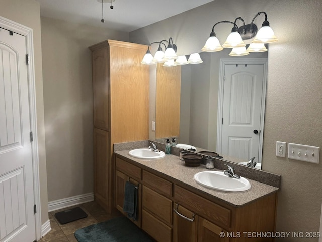 bathroom with a sink, baseboards, double vanity, and tile patterned floors