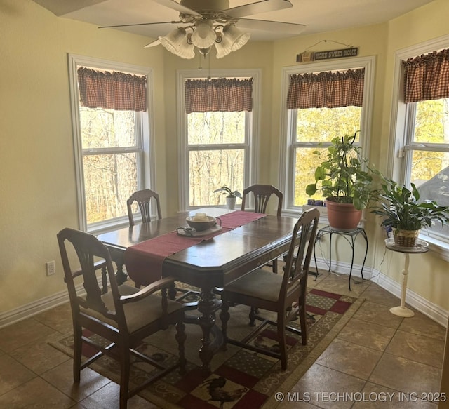 tiled dining area with a ceiling fan and baseboards