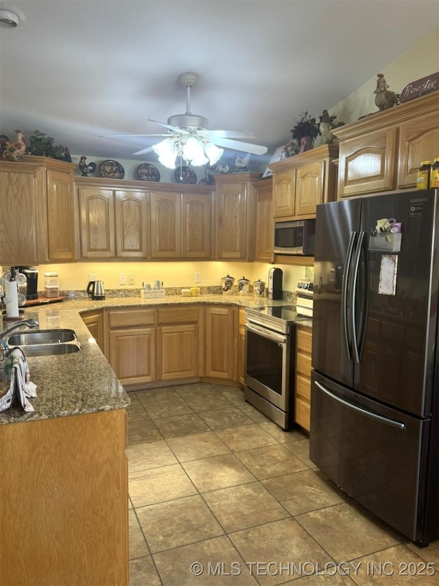 kitchen with light stone countertops, light tile patterned floors, appliances with stainless steel finishes, a ceiling fan, and a sink