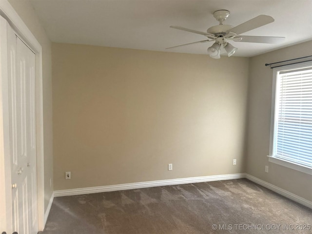 spare room with a ceiling fan, baseboards, and dark colored carpet