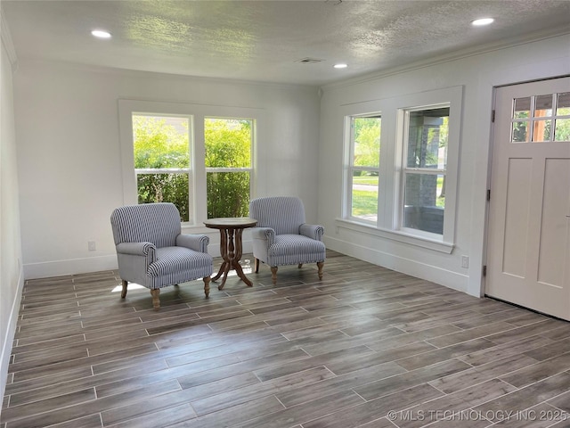 sitting room featuring a wealth of natural light, visible vents, wood finish floors, and a textured ceiling