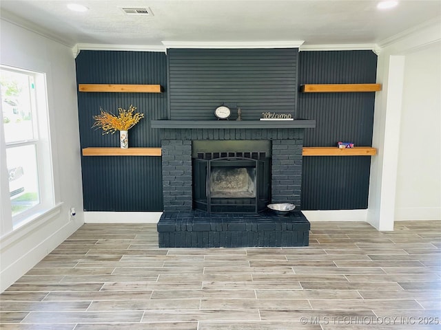 living area featuring visible vents, a healthy amount of sunlight, wood finish floors, and ornamental molding