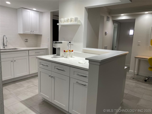 kitchen featuring a sink, a kitchen island, tasteful backsplash, white cabinetry, and recessed lighting