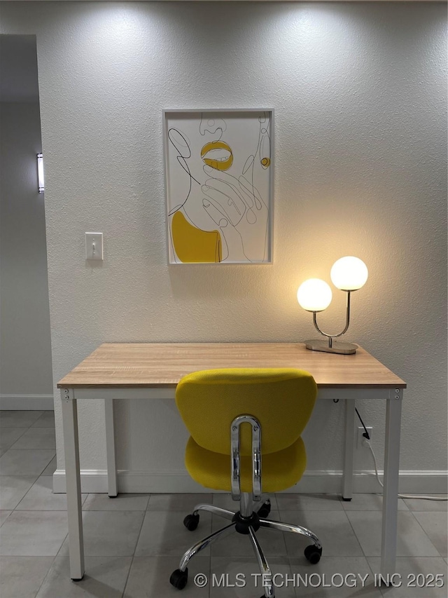 unfurnished office featuring tile patterned floors, baseboards, built in desk, and a textured wall