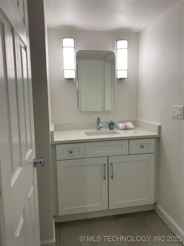 bathroom with baseboards, a textured ceiling, vanity, and tile patterned flooring