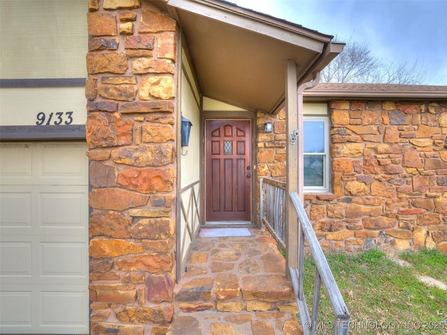 doorway to property featuring a garage and stone siding