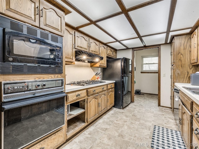 kitchen with brown cabinetry, baseboards, black appliances, light countertops, and under cabinet range hood