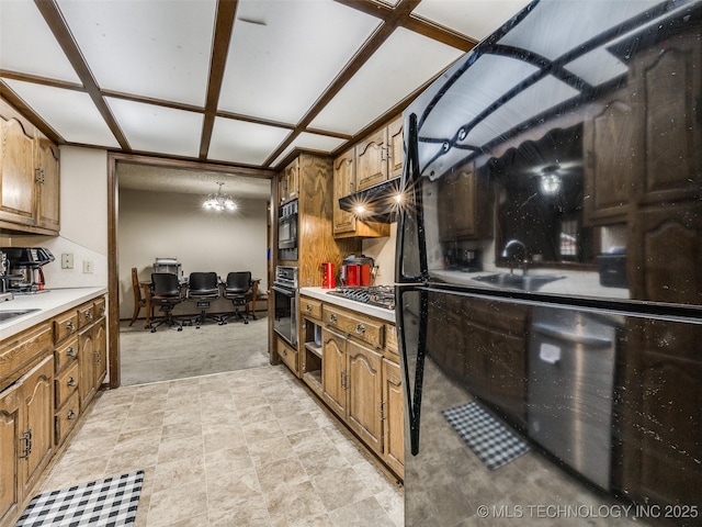 kitchen featuring an inviting chandelier, light countertops, brown cabinets, and appliances with stainless steel finishes