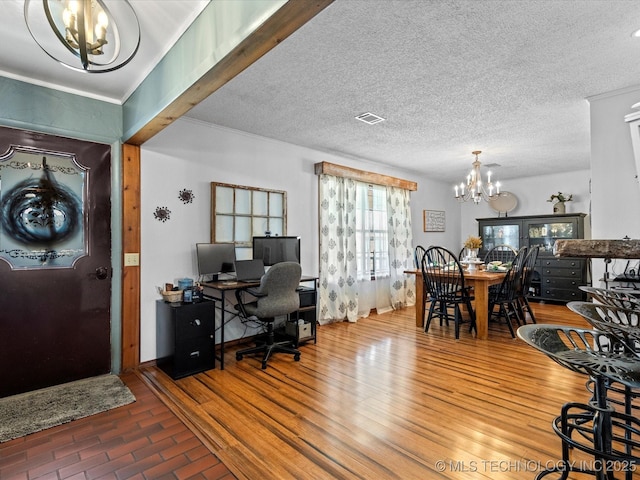 interior space featuring visible vents, a textured ceiling, an inviting chandelier, and wood finished floors