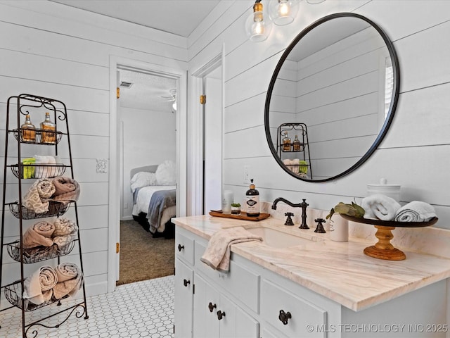 ensuite bathroom featuring vanity, wooden walls, and connected bathroom