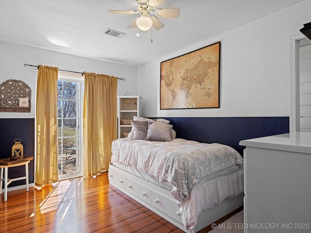 bedroom with ceiling fan, visible vents, wood finished floors, and access to outside