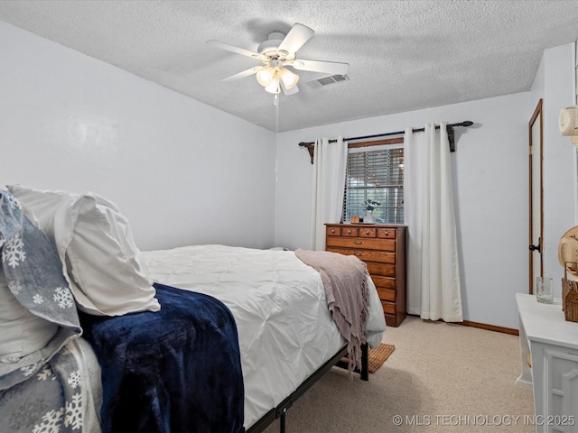 bedroom with visible vents, baseboards, light carpet, a textured ceiling, and a ceiling fan