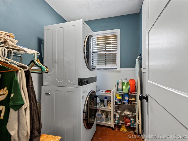 clothes washing area with laundry area, stacked washer and clothes dryer, and tile patterned floors