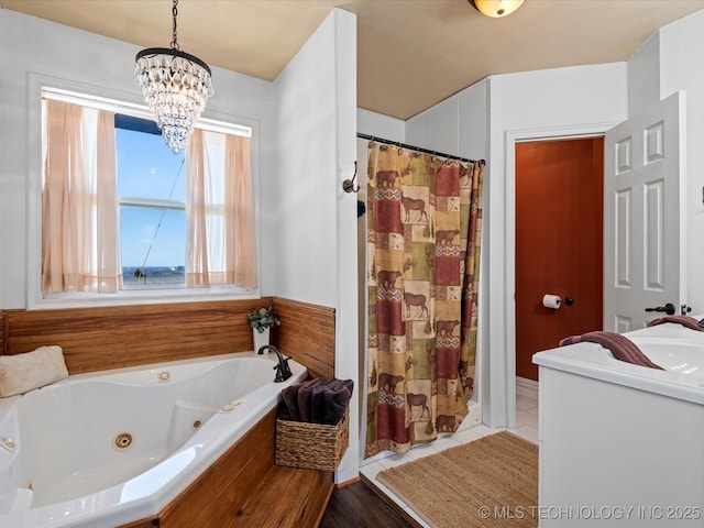 bathroom with tile patterned floors, a shower with curtain, a sink, a chandelier, and a whirlpool tub