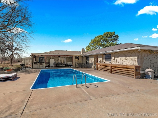 outdoor pool featuring outdoor dry bar, outdoor lounge area, and a patio