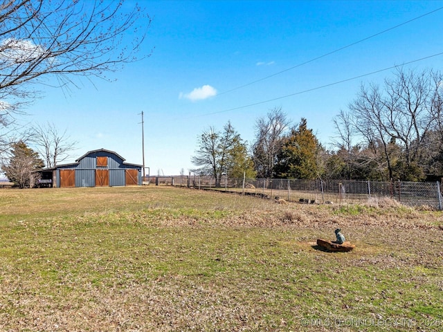 view of yard featuring a barn, an outdoor structure, and fence