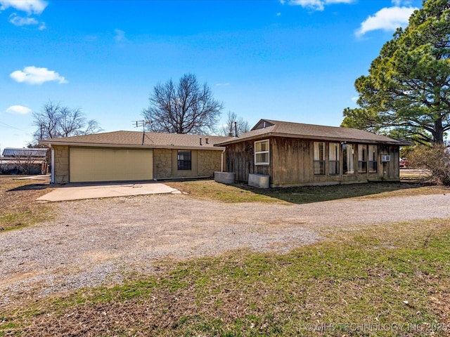 view of front of property featuring stone siding, an attached garage, and dirt driveway