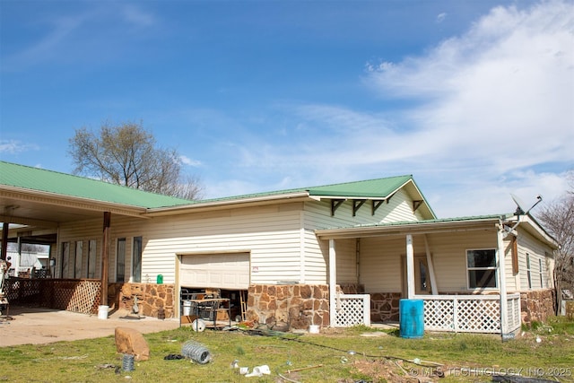 view of property exterior with stone siding, an attached garage, and metal roof