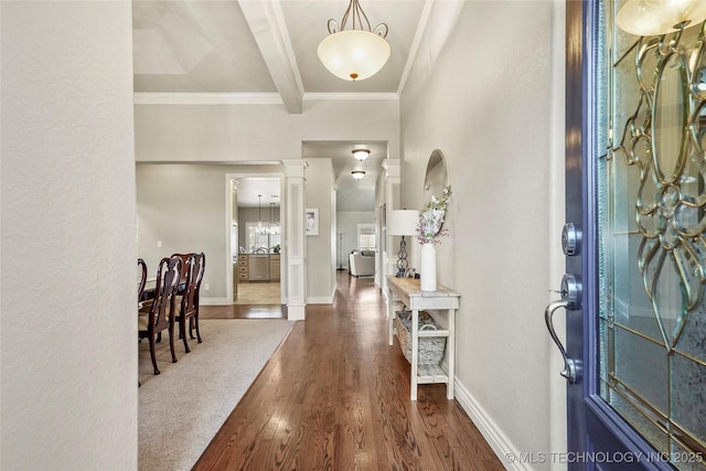 entryway featuring dark wood-style floors, baseboards, ornate columns, ornamental molding, and beamed ceiling