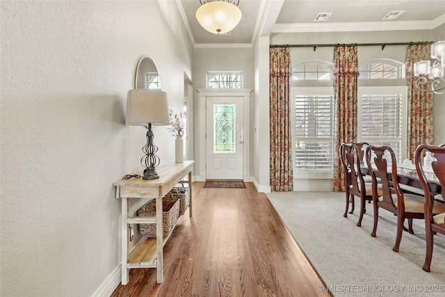 foyer featuring crown molding, wood finished floors, baseboards, and visible vents