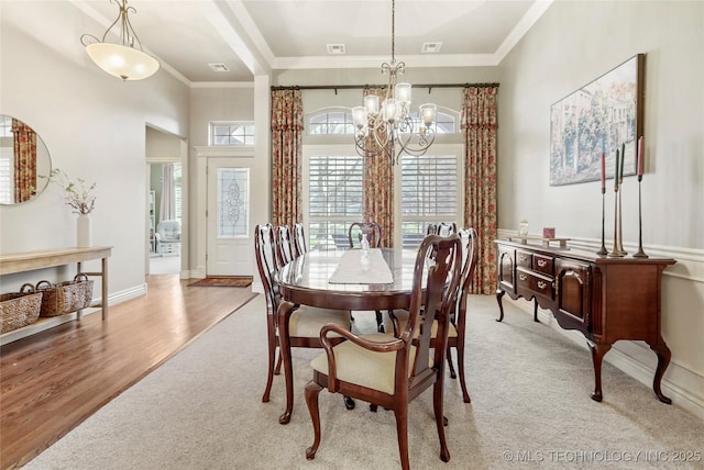 dining space featuring a notable chandelier, light wood-style flooring, crown molding, and baseboards