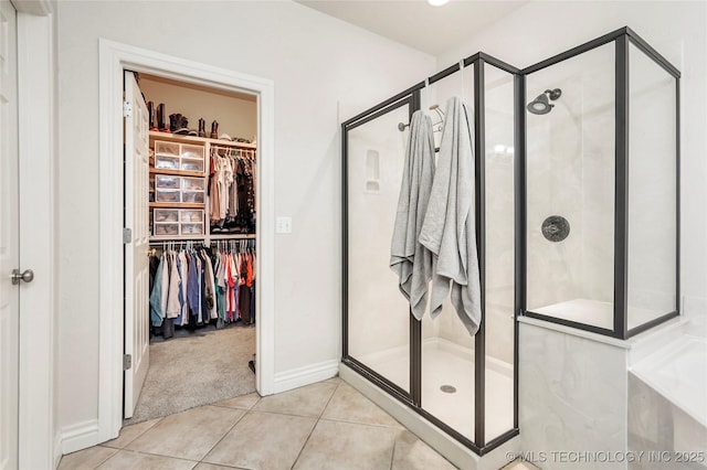 bathroom with tile patterned flooring, a shower stall, and a spacious closet