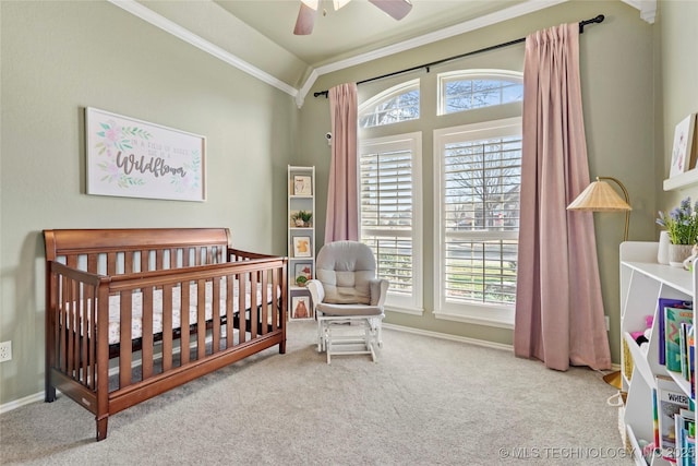 carpeted bedroom with a crib, multiple windows, baseboards, and ornamental molding