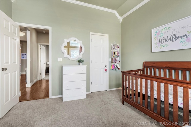 carpeted bedroom with crown molding, a nursery area, baseboards, and lofted ceiling