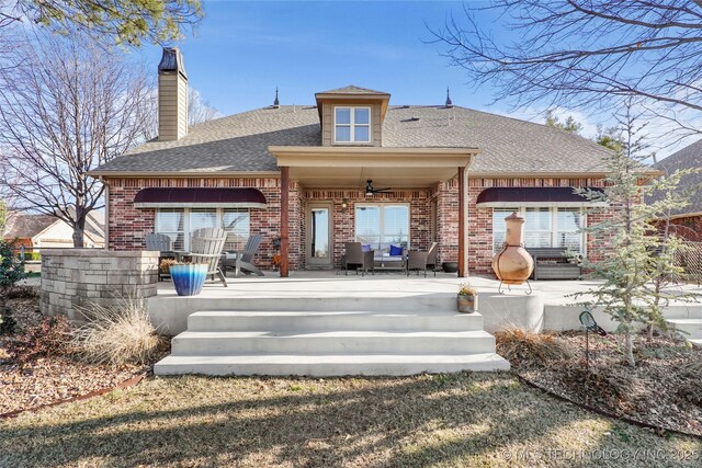 rear view of property with a patio, brick siding, and a shingled roof