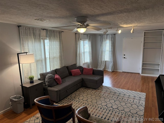 living room with visible vents, a textured ceiling, and wood finished floors