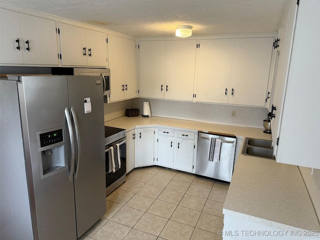 kitchen featuring light tile patterned flooring, a sink, light countertops, appliances with stainless steel finishes, and a textured ceiling