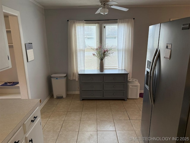 kitchen featuring stainless steel refrigerator with ice dispenser, crown molding, light countertops, light tile patterned floors, and ceiling fan