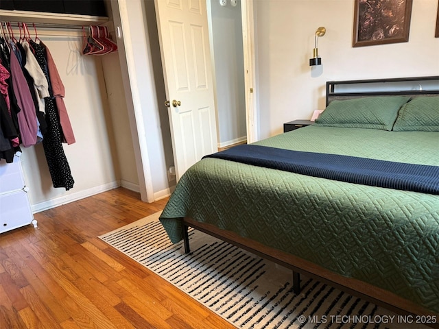 bedroom with a closet, baseboards, and wood finished floors