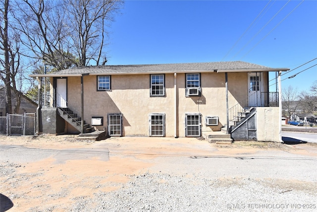 exterior space featuring stairs, fence, and stucco siding