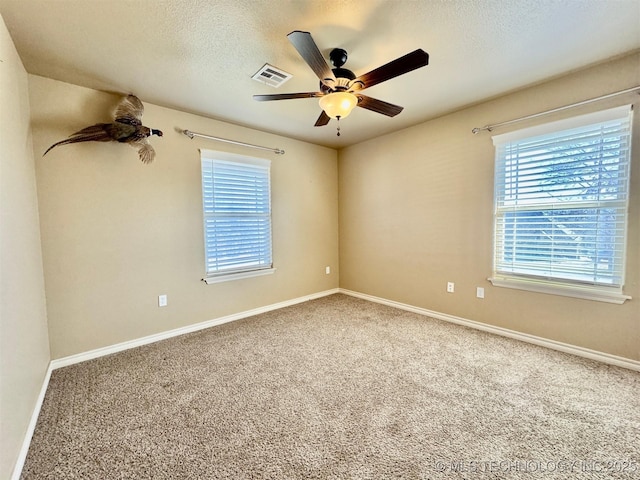 unfurnished room featuring visible vents, baseboards, ceiling fan, carpet floors, and a textured ceiling