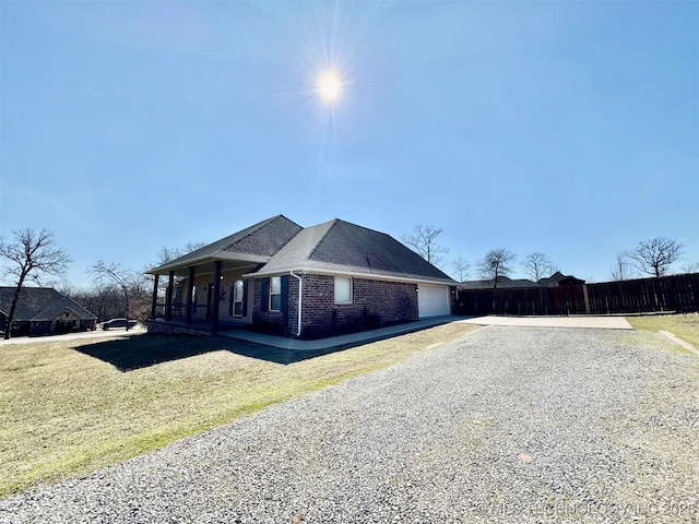 view of front of house featuring a front lawn, driveway, a porch, a garage, and brick siding