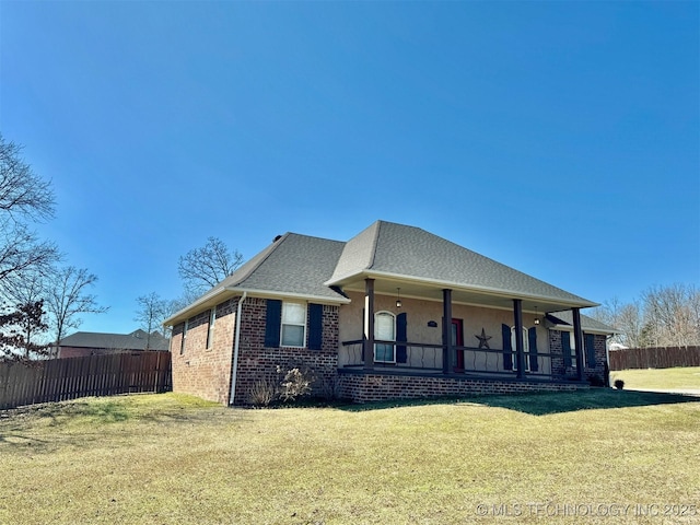 view of front of home featuring a front lawn, a porch, fence, and brick siding